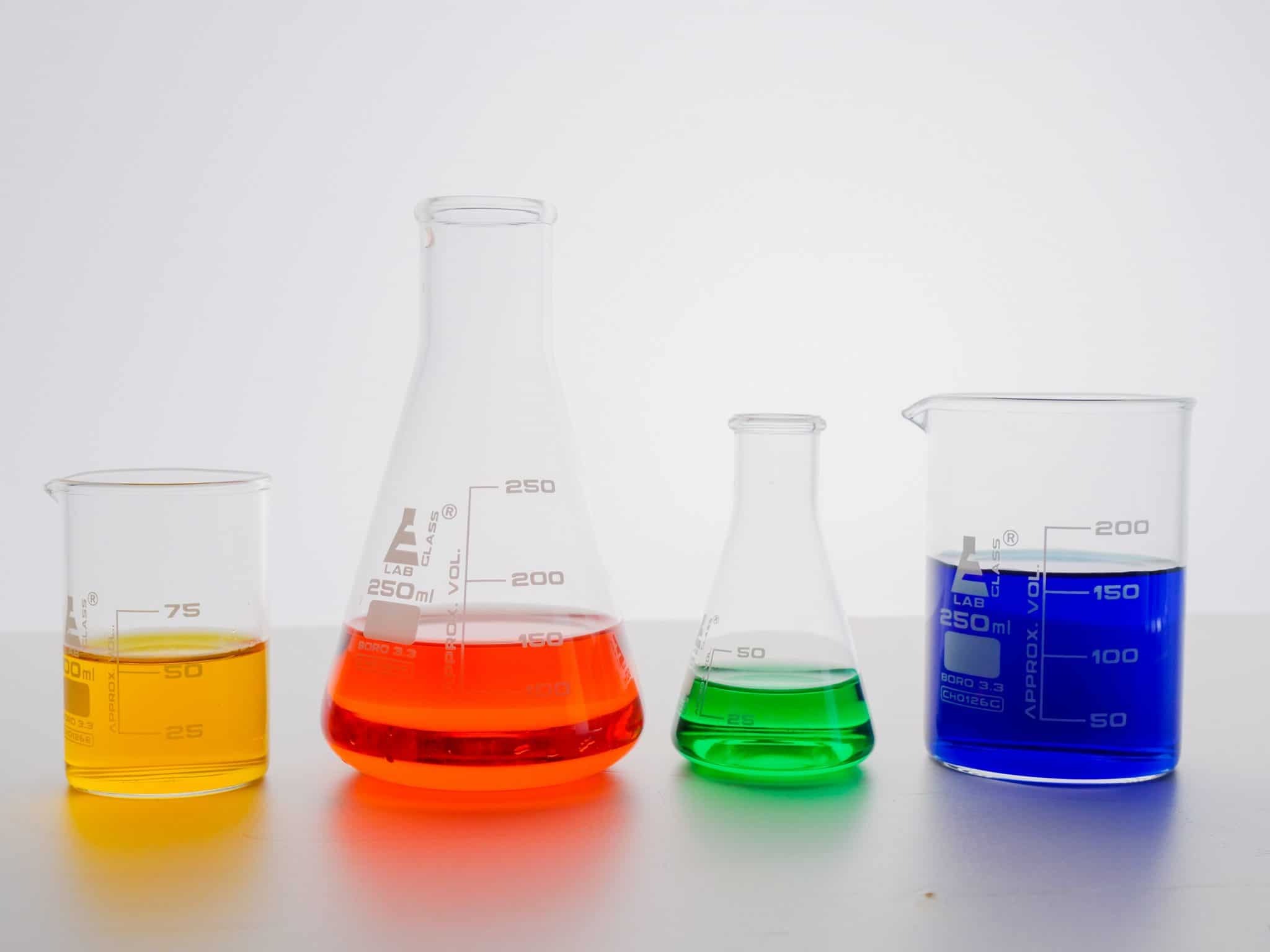 Different colored liquid chemicals in beakers.