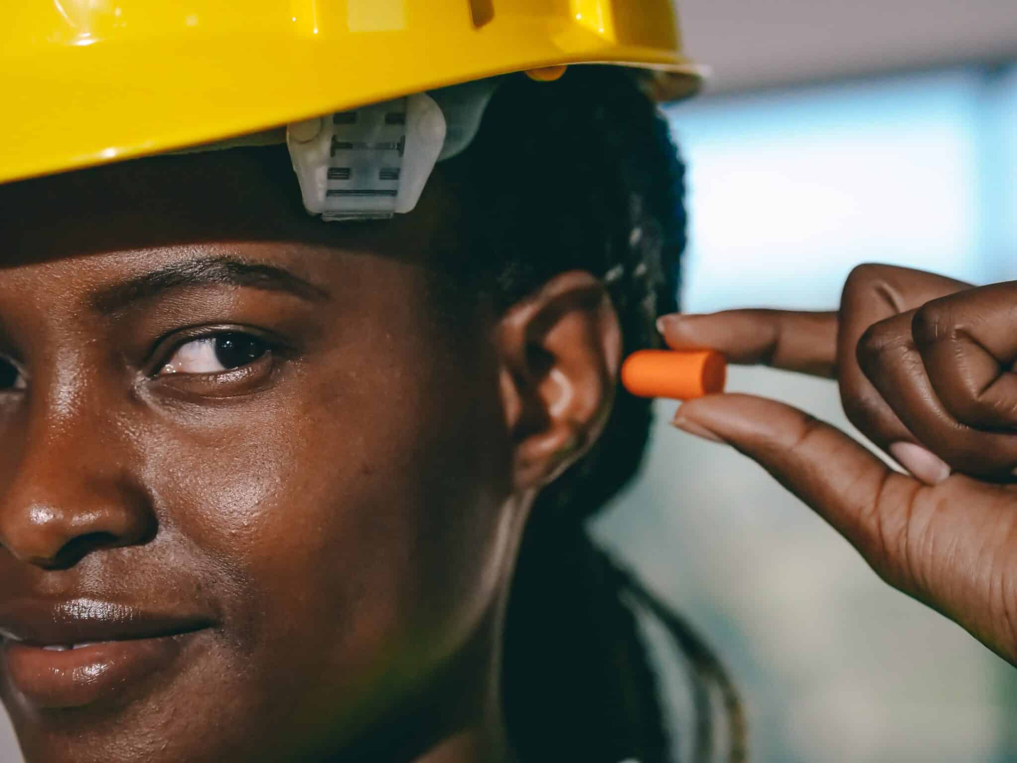 Female construction worker putting an earplug into her ear.