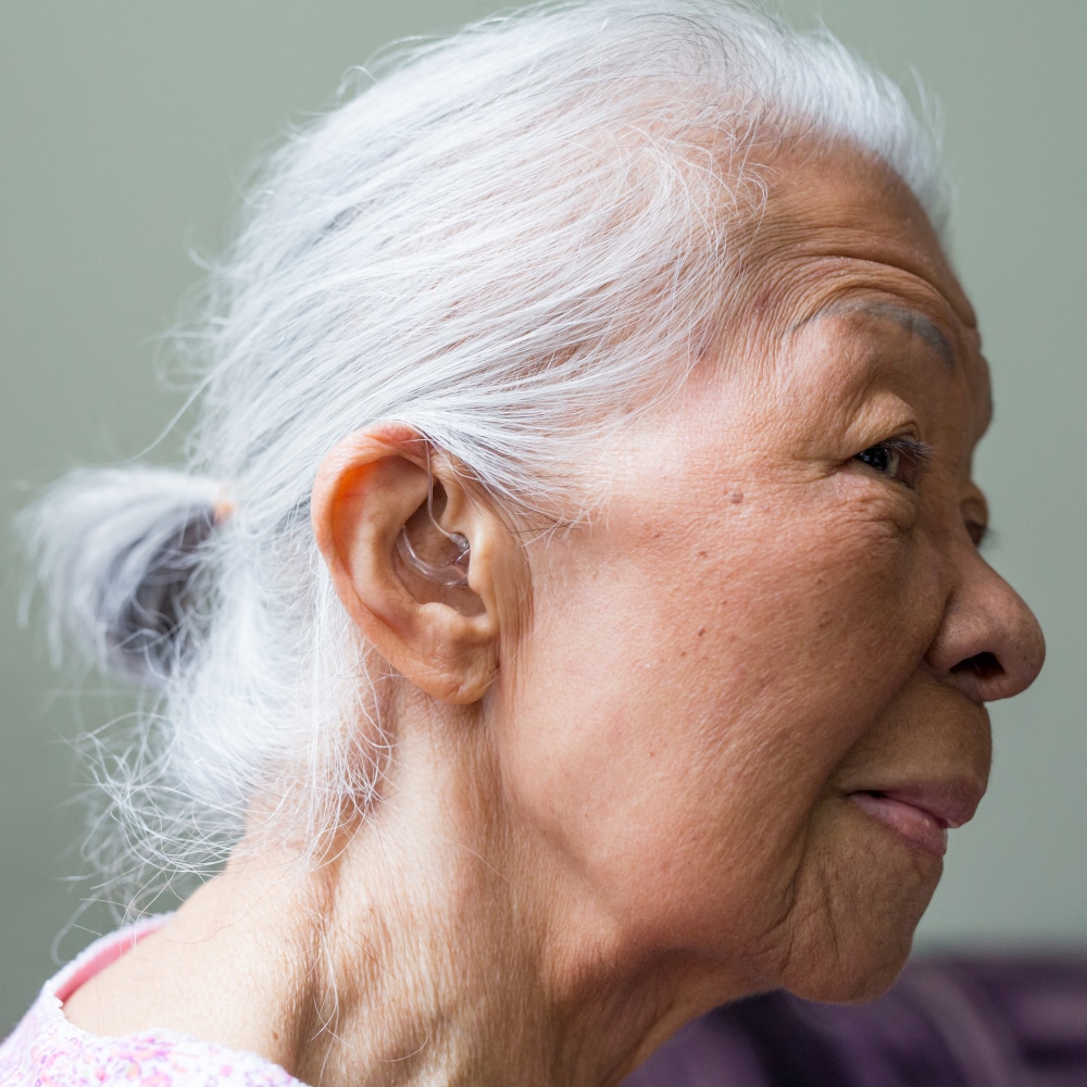 a woman shows off her ear and hearing aid