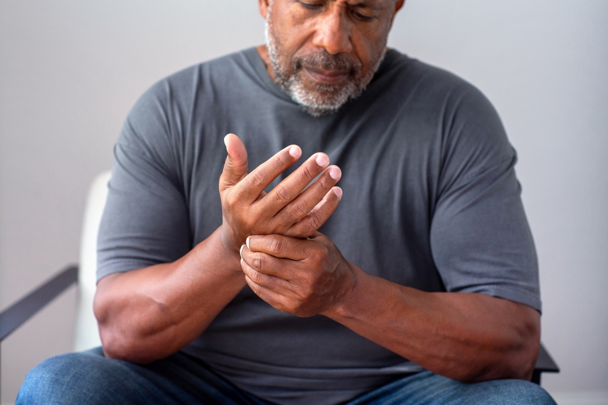 Man experiencing arthritis holding his hand.