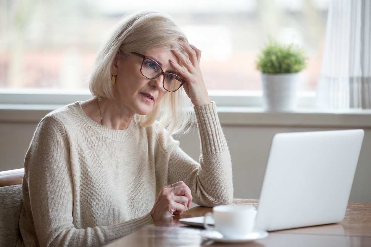 Woman feeling stressed and fatigued while working on laptop.