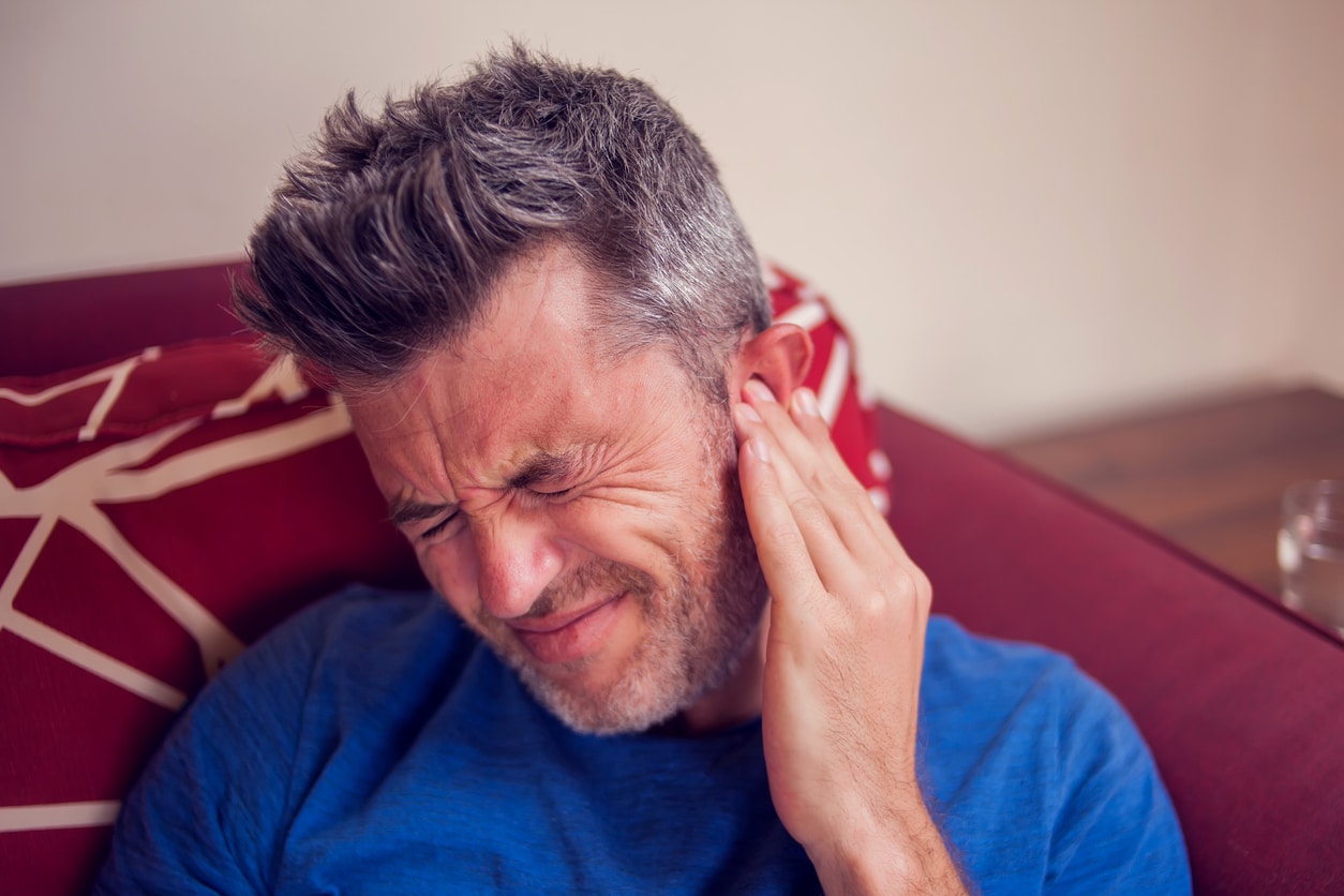Man with tinnitus holding his ear