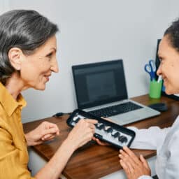 HHearing aid specialist showing her patient hearing aid styles
