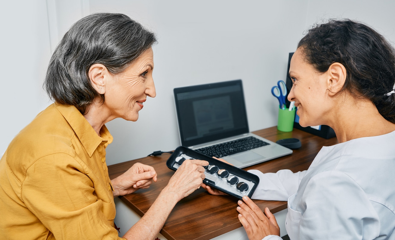 Hearing aid specialist showing her patient hearing aid styles