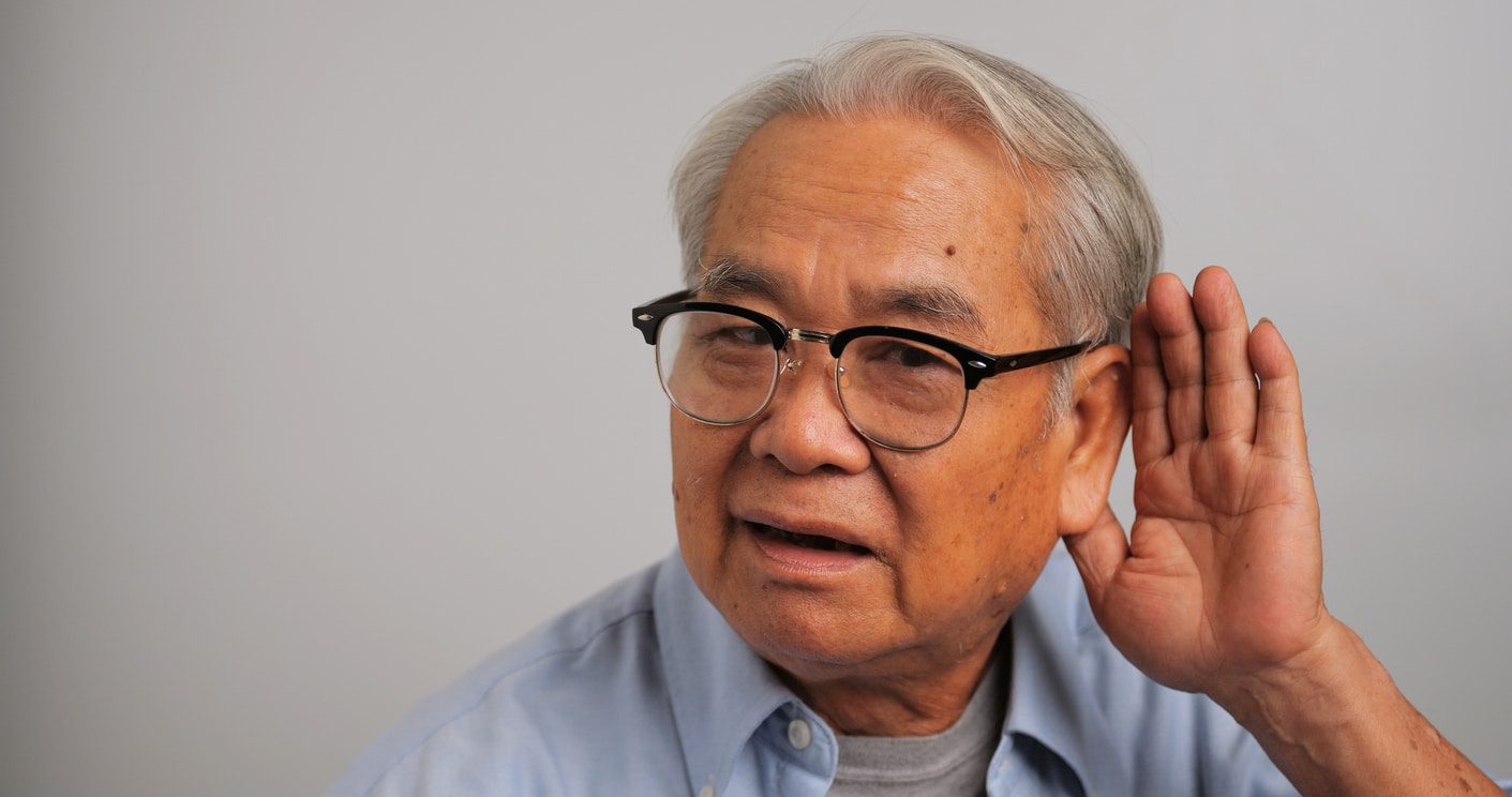 Man holds hand behind ear